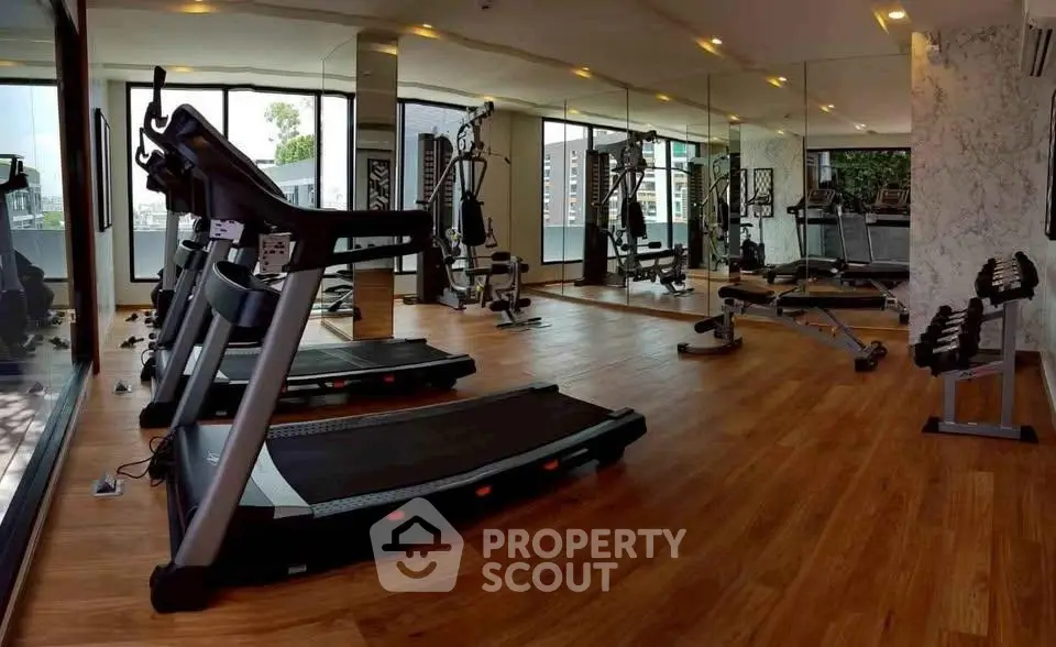 Modern gym with state-of-the-art equipment and mirrored walls in luxury apartment building.