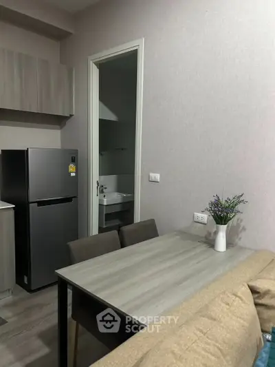 Modern kitchen and dining area with sleek fridge and stylish table setting.