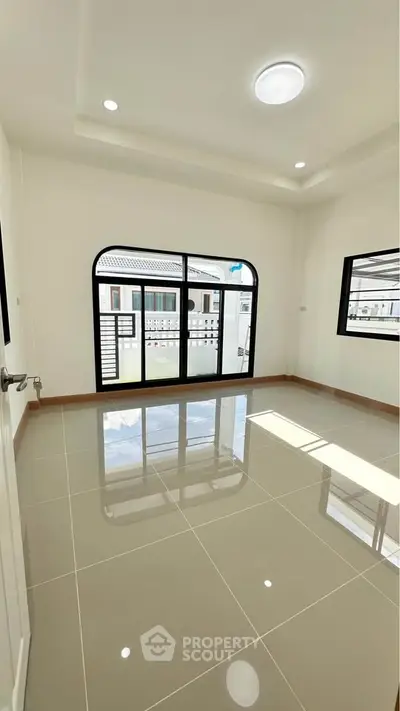 Bright and spacious room with large windows and glossy tiled floor, perfect for modern living.