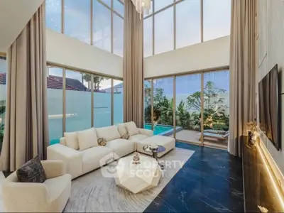 Luxurious living room with high ceilings and pool view, featuring elegant decor and large windows.