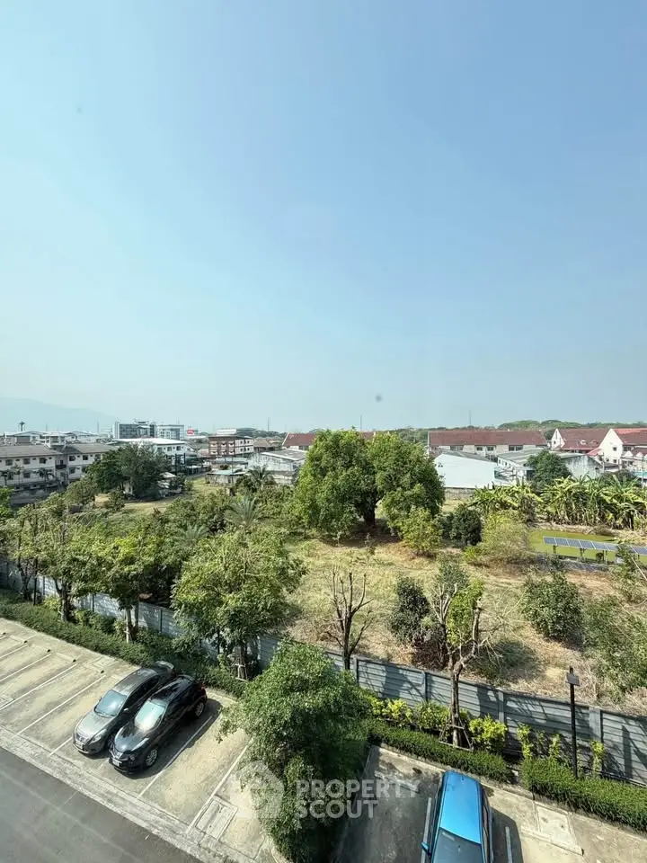 Scenic view from a high-rise overlooking lush greenery and residential area, perfect for serene living.