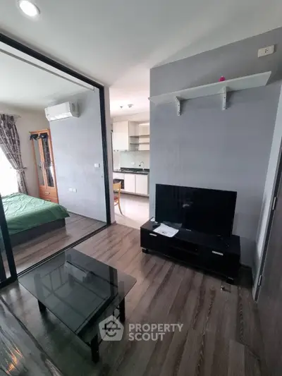 Modern apartment living room with glass partition and view into bedroom and kitchen