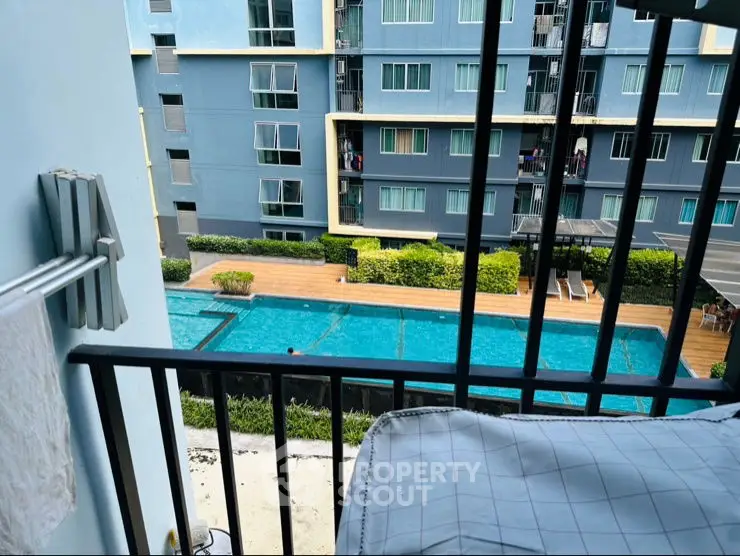 Modern apartment balcony overlooking a luxurious swimming pool and garden area.