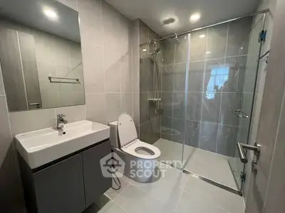 Modern bathroom with glass shower and sleek fixtures in contemporary apartment.