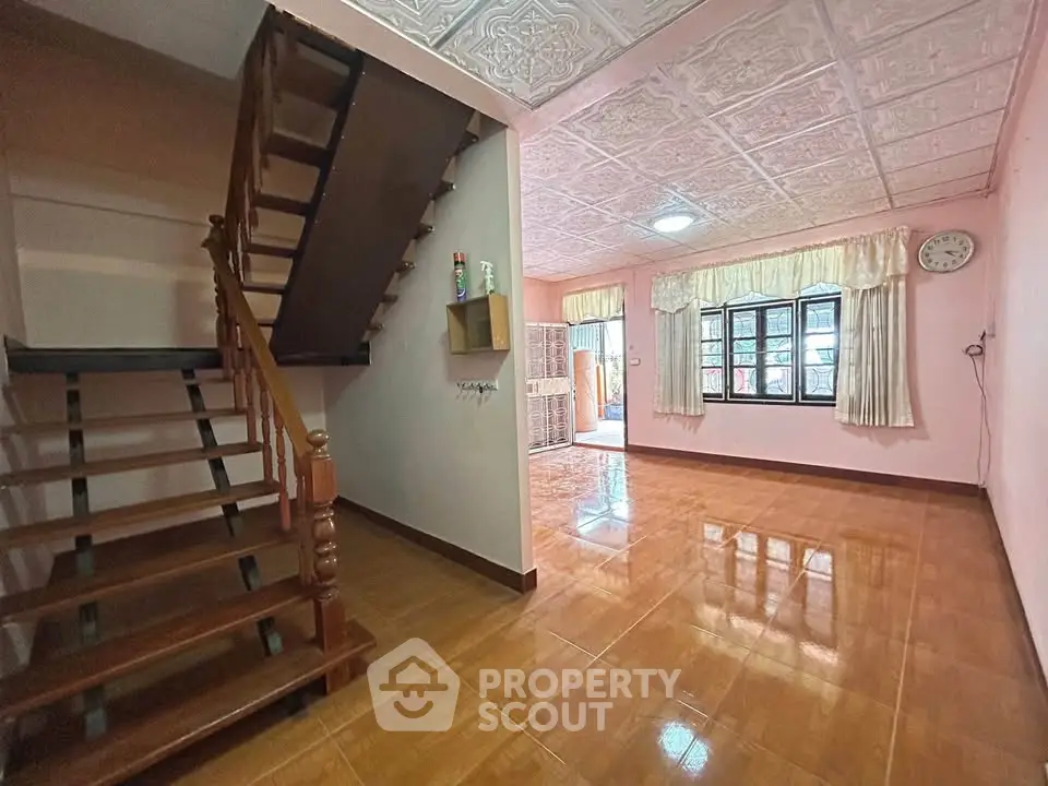 Spacious living room with wooden staircase and large windows in a cozy home.