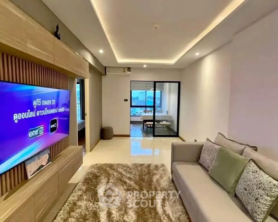 Modern living room with sleek design and large TV, featuring cozy sofa and stylish decor.