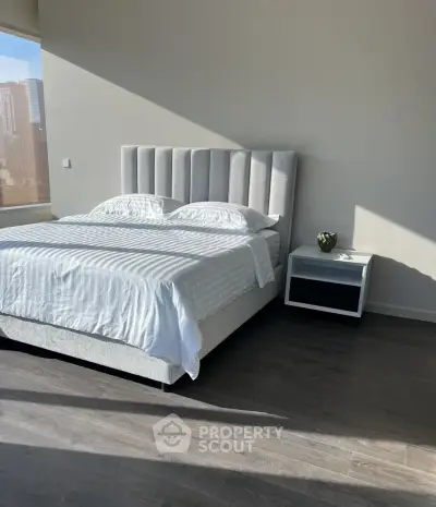 Modern bedroom with stylish bed and natural light in a high-rise apartment.