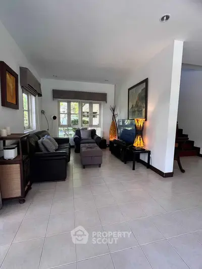 Spacious living room with modern decor and natural light, perfect for relaxation and entertainment.