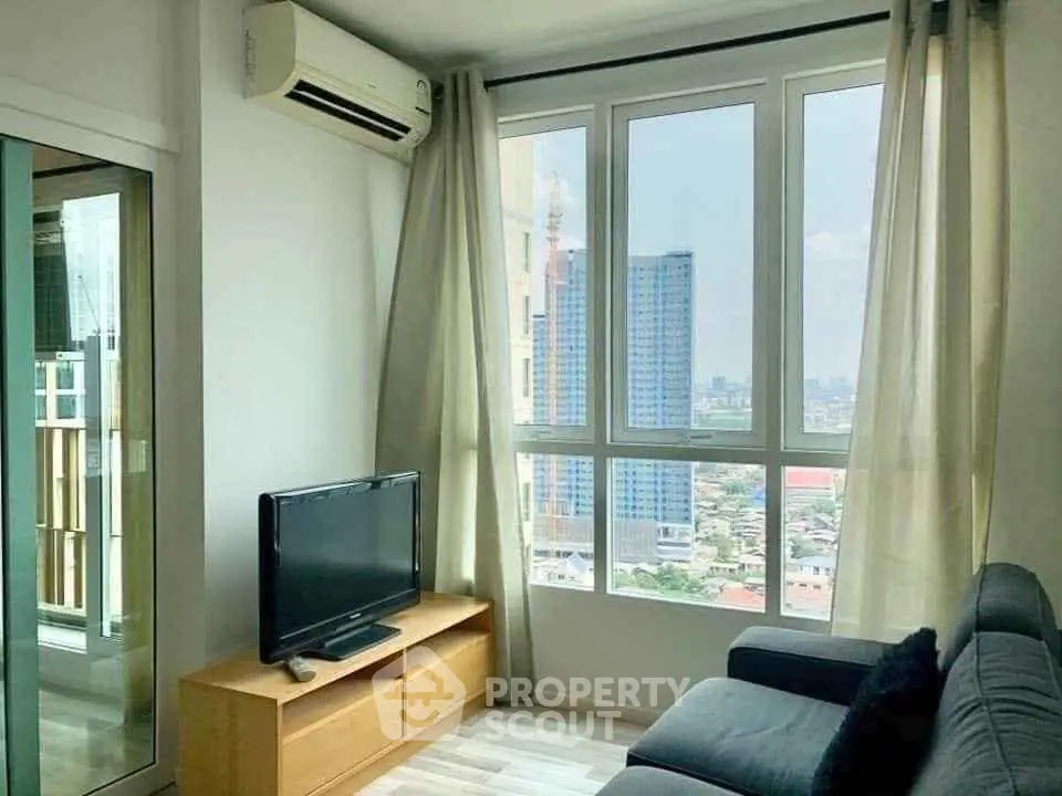 Bright living room with large windows offering city views, modern furniture, and air conditioning.