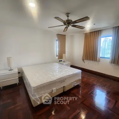 Spacious bedroom with hardwood floors and ceiling fan in modern apartment.