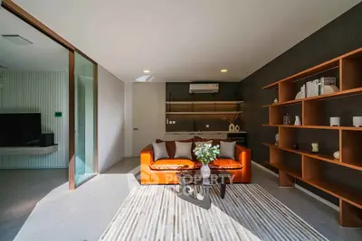 Modern living room with stylish orange sofa and elegant shelving, flooded with natural light.