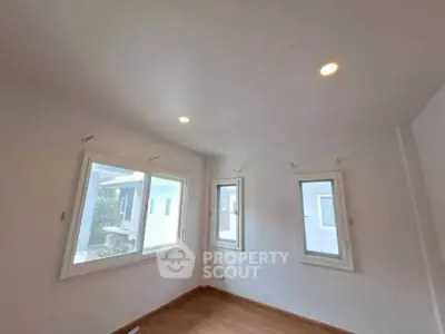 Bright room with large windows and wooden flooring, ideal for a cozy living space.