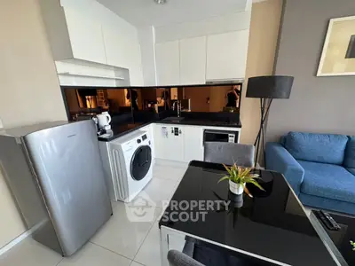 Modern kitchen with sleek appliances and cozy living area in open layout apartment.