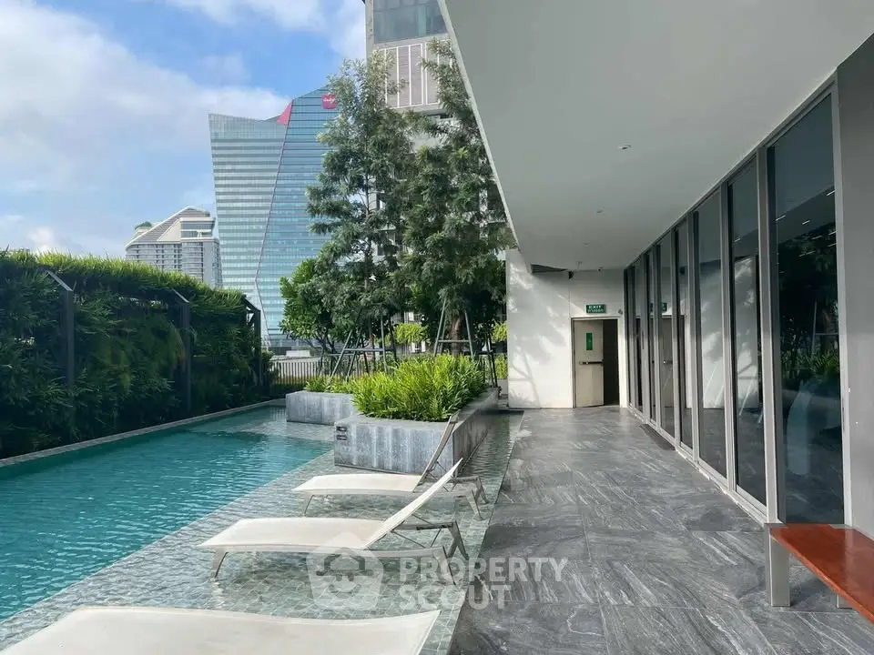 Luxurious rooftop pool area with modern lounge chairs and city skyline view.