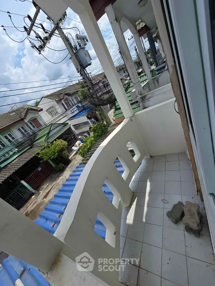 Charming balcony view in a residential neighborhood with tiled flooring and street view.