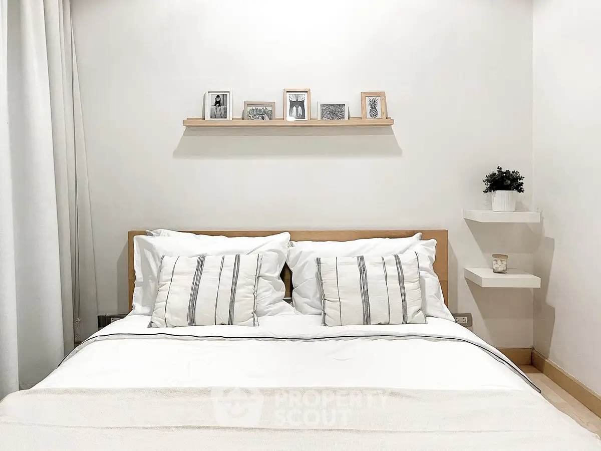 Cozy bedroom with minimalist decor and stylish framed photos on shelf.