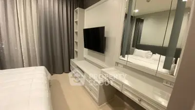 Modern bedroom with sleek TV unit and mirrored vanity in stylish apartment.