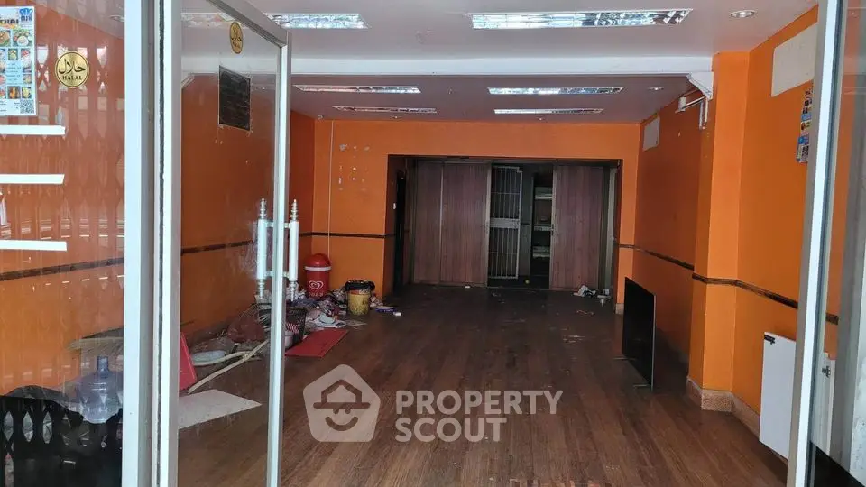 Spacious commercial property with vibrant orange walls and wooden flooring, ideal for retail or office space.