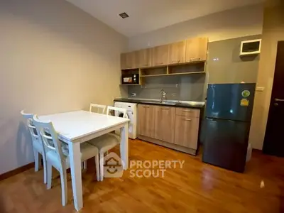 Modern kitchen with dining area, featuring wooden cabinets and sleek appliances.