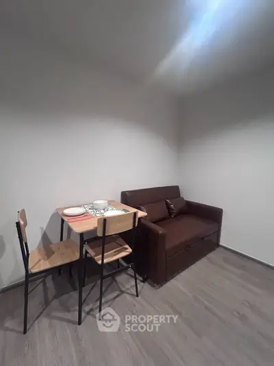 Cozy compact living room with a small dining table and a brown sofa, perfect for urban living.