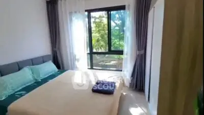 Bright bedroom with large window and garden view, featuring modern decor and cozy bedding.