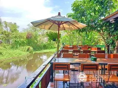 Charming riverside outdoor dining area with lush greenery and serene water view.