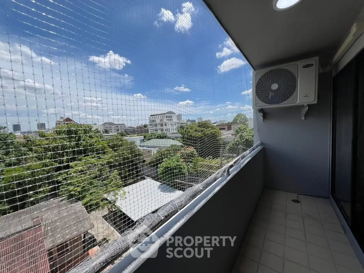 Spacious balcony with safety netting and air conditioning unit, offering a scenic city view.