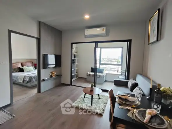 Modern open-plan living room with dining area and view into cozy bedroom, featuring stylish decor and ample natural light.