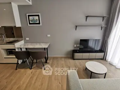 Modern living room with stylish furniture and open kitchen layout, featuring natural light and elegant decor.