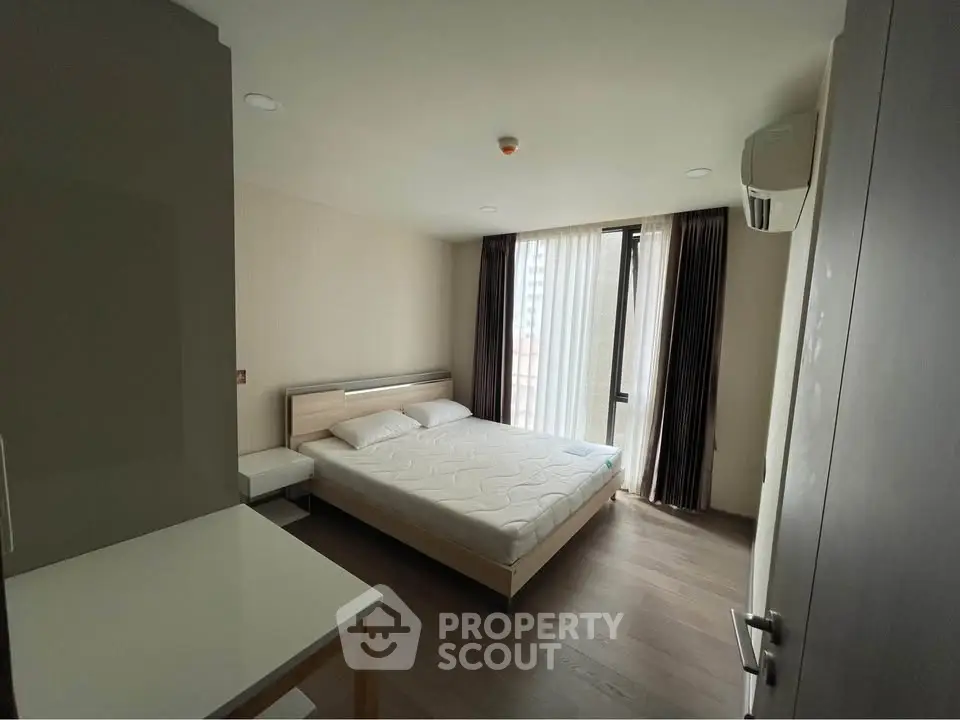 Modern bedroom with large window and minimalist design in a high-rise apartment.