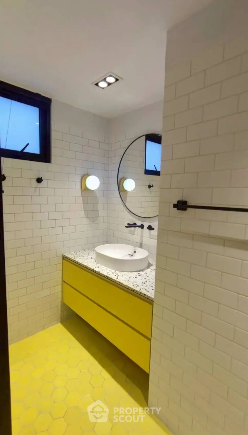 Modern bathroom with yellow accents and stylish round mirror