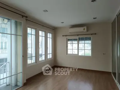 Spacious empty room with large windows and wooden flooring, perfect for customization.