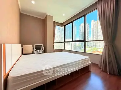 Spacious bedroom with large windows offering stunning city views in a modern high-rise apartment.