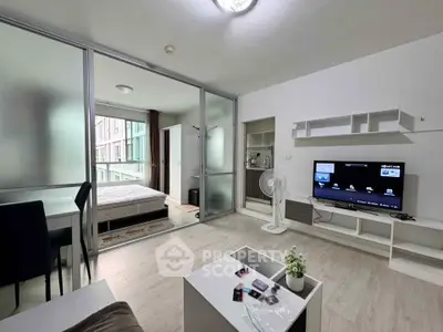 Modern studio apartment with open layout, featuring a cozy living area and bedroom separated by glass sliding doors.
