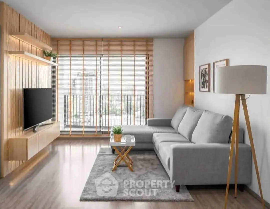 Modern living room with stylish decor, large window, and cozy gray sofa in a bright apartment.