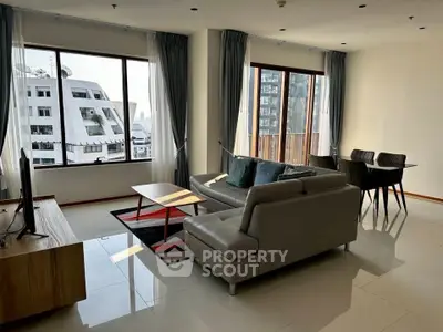 Spacious modern living room with elegant decor and large windows offering city views.