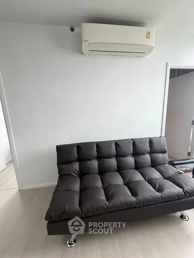 Modern living room with sleek black sofa and wall-mounted air conditioner, perfect for urban living.