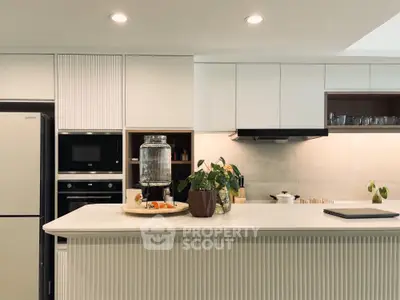Modern kitchen with sleek cabinetry and built-in appliances, featuring a stylish countertop and elegant lighting.