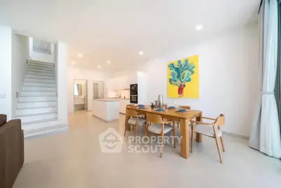 Spacious modern living room with open kitchen and dining area, featuring stylish decor and natural light.