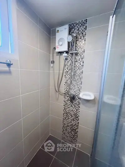 Modern bathroom shower area with sleek tiles and water heater.