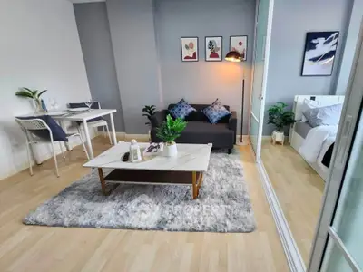 Modern living room with cozy decor and adjacent bedroom, featuring stylish furniture and art pieces.