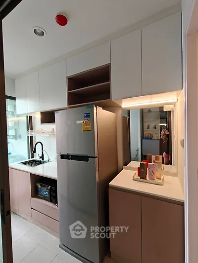 Modern kitchen with sleek cabinetry and stainless steel fridge in a compact layout.