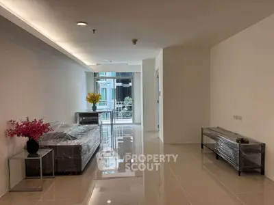 Spacious modern living room with sleek tile flooring and large windows offering natural light.