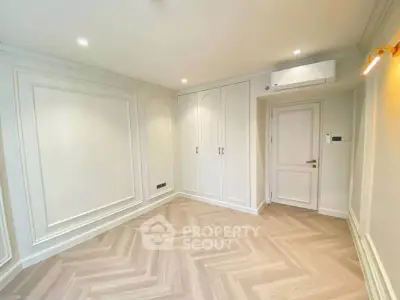 Elegant empty room with herringbone flooring and built-in wardrobe, perfect for customization.