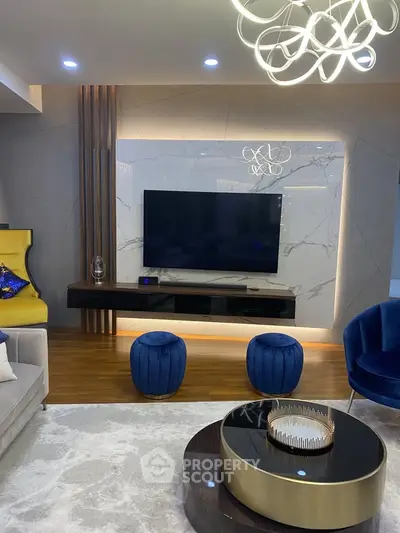Luxurious modern living room with elegant decor and large flat-screen TV, featuring plush seating and stylish lighting.