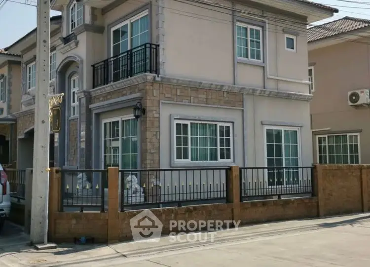 Charming two-story house with elegant stone facade and fenced yard in a serene neighborhood.
