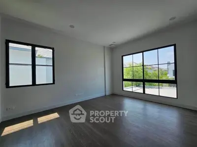 Spacious empty room with large windows and wooden flooring, perfect for customization.