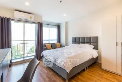 Modern bedroom with large window and balcony access, featuring stylish furniture and natural light.