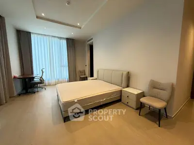 Spacious modern bedroom with elegant furnishings and large window for natural light.