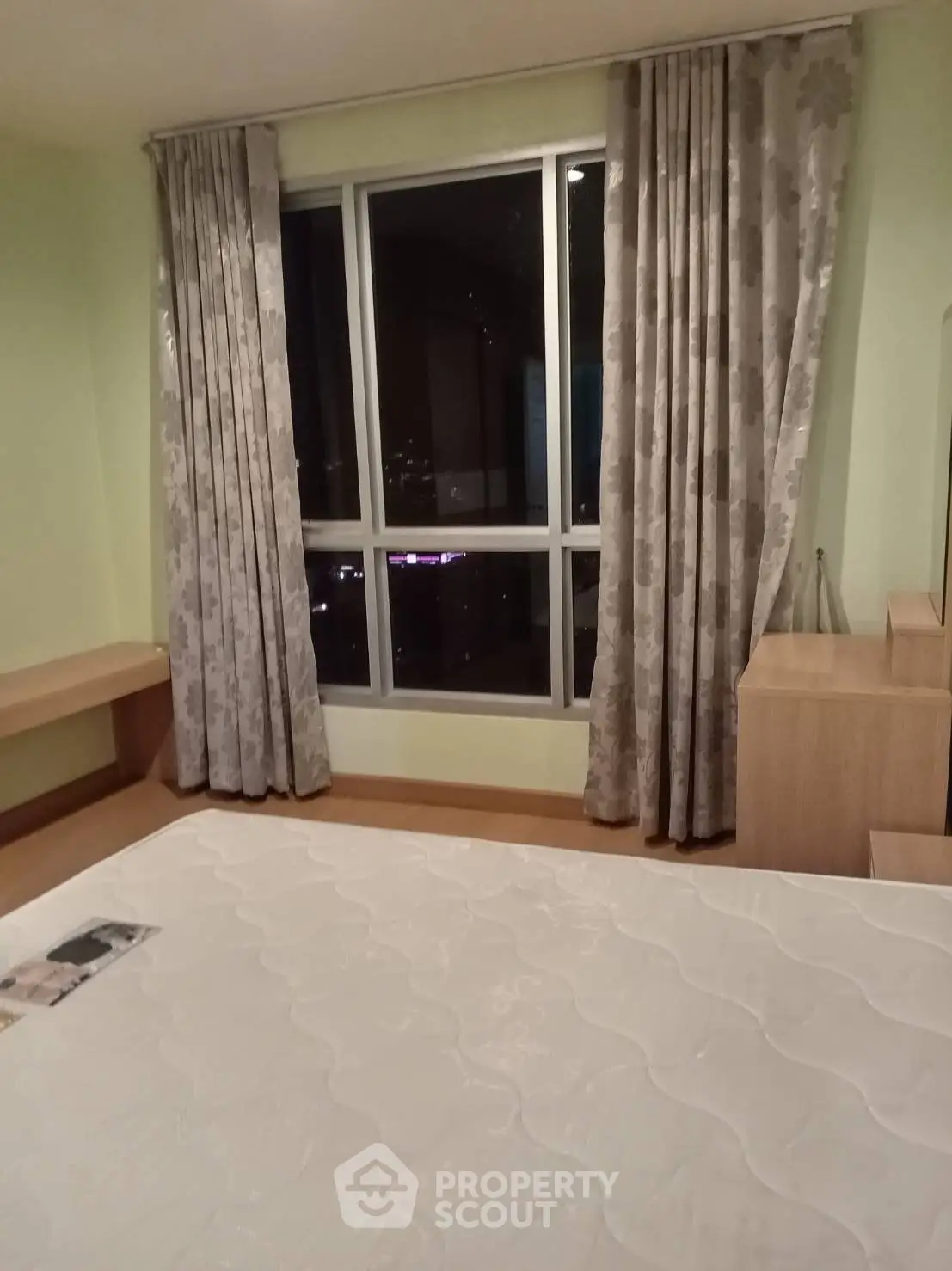 Cozy bedroom with large window and elegant curtains, perfect for city living.